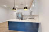 Located at 5020 Limelight Ln in Charlotte, NC, this two-story home offers a thoughtfully designed layout across two floors. The main level houses an open-concept kitchen and living area, where a striking blue-paneled island with a white quartz countertop and undermount sink serves as the centerpiece. White shaker cabinets, a subway tile backsplash, stainless steel appliances, and dual black pendant lights complete the modern kitchen. Light hardwood-style flooring extends throughout the living areas, adding warmth and continuity. A pantry, hallway, and attached garage with an automatic opener round out the ground floor. The upper level hosts all three bedrooms, including a well-sized primary suite, along with four full bathrooms. The bathrooms are finished with white shaker vanities, quartz countertops, and light wood-style flooring. Bedrooms feature neutral walls, large windows that invite natural light, and ceiling fans for comfort. Two patios provide outdoor living options, while ample closet space and a dedicated laundry room enhance everyday functionality. The home's clean, contemporary aesthetic and practical layout make it a well-rounded residence in Charlotte.