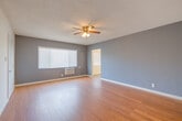 Located at 6100 West Blvd in the Hyde Park neighborhood of Los Angeles, this single-floor unit offers a practical and comfortable layout across several well-defined living spaces. The main living area is finished with warm hardwood-style flooring and features a textured ceiling with a ceiling fan and integrated light fixture. Walls are painted in a calm slate blue accent tone, complemented by crisp white baseboards, creating a clean and modern aesthetic throughout.

The living space opens into additional rooms, each consistently finished with the same hardwood-style flooring, ceiling fans, and slate-toned walls. The bedrooms are well-sized, each equipped with a wall-unit air conditioner and windows fitted with horizontal blinds, allowing for natural light and ventilation control.

The kitchen features white cabinetry, a stainless steel refrigerator, a gas range, and tile flooring in a neutral diamond pattern, providing ample functionality in a compact footprint.

The bathroom is finished in a clean, all-white palette with marble-look tile flooring, a white vanity with chrome fixtures, a wall mirror with storage shelving, and a shower-tub combination with a privacy window above. The overall ambiance of the unit is bright, neutral, and move-in ready, offering a straightforward and livable space in a well-situated Los Angeles location.