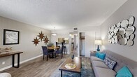 This single-floor, one-bedroom, one-bathroom unit offers a thoughtfully laid-out living space that maximizes every square foot. The open-concept main area seamlessly connects the living room, dining area, and kitchen, creating a cohesive and functional space. Wood-look flooring runs throughout, adding warmth and visual continuity across all rooms.

The living room provides a comfortable gathering area, with neutral gray walls and access to a dedicated closet. The dining area is defined by a pendant light overhead and sits directly adjacent to the kitchen, making the space ideal for everyday meals. The kitchen features white cabinetry, stainless steel appliances including a refrigerator and electric range, and a practical layout suited for home cooking.

The bedroom is a standout space, distinguished by a bold burnt-orange accent wall that adds striking visual character. It accommodates a full-sized bed comfortably, includes a window that brings in natural light, and benefits from access to a dedicated closet with hanging rod storage.

The bathroom is clean and functional, featuring a full tub and shower combination with white tile surround. A textured ceiling is consistent throughout the unit, complementing the overall design. This efficiently designed residence offers a complete set of essential spaces in a compact and cohesive floor plan.