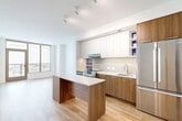 This thoughtfully designed one-bedroom, one-bathroom unit at 600 Howard Rd SE in Washington, DC, offers a modern open-concept layout with clean lines and contemporary finishes throughout. Light wood flooring flows seamlessly across the living, dining, and kitchen areas, creating a cohesive and airy feel.

The kitchen is a standout feature, boasting warm wood cabinetry paired with crisp white upper cabinets, a textured tile backsplash with purple accent shelving, stainless steel appliances, and a central island with a white countertop — ideal for both cooking and casual dining. The living area is bright and open, benefiting from large floor-to-ceiling windows that invite abundant natural light and offer elevated outdoor views.

The bedroom is a well-proportioned retreat with its own large corner window framing scenic views, and is complemented by two dedicated closets — one featuring a configurable shelving and hanging system for ample storage. The full bathroom includes a soaking tub, tile surround, and a wood-accented vanity with clean, neutral tile flooring.

Additional highlights include an in-unit laundry area, an entrance with a modern door, and a private patio for outdoor enjoyment. The space combines functional design with modern aesthetics throughout.
