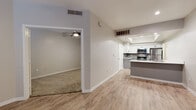 Located in Phoenix, Arizona, this single-floor residence offers a well-designed layout with modern finishes throughout. The open-concept living and kitchen area is anchored by light wood-look flooring that creates a clean, cohesive aesthetic. The kitchen is a standout feature, showcasing white upper cabinetry paired with gray lower cabinets, a subway tile backsplash, light quartz countertops, and a peninsula with a built-in sink — ideal for both meal preparation and casual dining. Stainless steel appliances, including a refrigerator, electric range, and microwave, complete the culinary space. A tray ceiling detail above the kitchen adds subtle architectural interest. The living area flows into a carpeted bedroom equipped with a ceiling fan and a window that allows natural light to filter in. The entryway features wood-look flooring, a built-in niche, and a window alongside the front door, providing a welcoming first impression. A walk-in closet with wire shelving and plush carpet offers generous storage. The bathroom is cleanly appointed with a white vanity featuring black hardware, a combination tub and shower, and wood-look flooring. Throughout the space, neutral tones and consistent finishes create a calm, modern atmosphere.