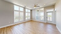 Located at 120 Hollis Rd in Charlotte, NC, this well-appointed one-bedroom, three-bathroom residence offers a thoughtfully designed single-floor layout. The open-concept living and kitchen area is anchored by expansive floor-to-ceiling windows that flood the space with natural light and provide sweeping views of the surrounding Charlotte skyline and greenery. Light hardwood-style flooring runs throughout the main living areas, complemented by a ceiling fan and recessed lighting.

The kitchen is a standout feature, showcasing tall shaker-style cabinetry in a soft gray tone, dark quartz countertops, stainless steel appliances including a side-by-side refrigerator and range, a wall-mounted range hood, and a large center island with pendant lighting — ideal for both cooking and entertaining.

The generously sized primary bedroom is carpeted for comfort, features large windows with outdoor views, a ceiling fan, and direct access to a walk-in closet with built-in shelving and hanging rods. The primary bathroom impresses with marble-tiled walls and flooring, a glass-enclosed walk-in shower, and a white vanity with dark hardware. Additional bathrooms provide practical functionality with clean, neutral finishes throughout. The overall ambiance is modern, bright, and move-in ready.