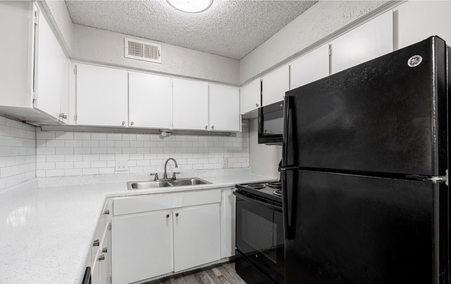 A sleek, modern kitchen with ample storage and updated appliances. - Arbor Park Apartments