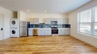 Located at 723 Mount Vernon Ave in Columbus, OH, this thoughtfully designed one-bedroom, one-bathroom unit offers a clean, modern aesthetic with efficient use of space throughout. The open-concept kitchen and living area serves as the heart of the home, featuring warm light wood flooring, recessed lighting, and a contemporary globe chandelier. The kitchen is well-appointed with gray shaker-style cabinetry, white quartz countertops, a blue-gray subway tile backsplash, and a full suite of stainless steel appliances, including a refrigerator, range, microwave, and dishwasher. A large window floods the living area with natural light while offering views of the surroundings. In-unit stacked washer and dryer add everyday convenience. The bedroom is a bright, comfortable retreat with its own large window and warm wood flooring. The bathroom features stone tile flooring, a wood-toned vanity with a white countertop, and a glass-enclosed shower. Three closets provide generous storage throughout the unit, including a walk-in closet accessible from the bathroom. Crisp white walls and consistent wood-look flooring tie the entire space together in a cohesive, contemporary style.