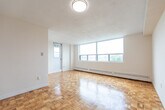 Located at 2677 Kipling Ave in Toronto's northwest end, this 2-bedroom, 1-bathroom unit offers a practical and well-organized layout across a single floor. The space is immediately welcoming, with warm parquet flooring found throughout the hallway, bedrooms, and main living areas, lending a classic character to the interior.

The living area is a standout feature, bathed in natural light from a wide bank of windows that frame open outdoor views of the surrounding neighbourhood and treetops. Baseboard heating runs along the perimeter, ensuring comfortable warmth throughout the seasons.

Both bedrooms are well-proportioned and bright. The primary bedroom benefits from natural light through its own window with outdoor views, while both rooms continue the warm parquet flooring and feature clean, neutral walls offering a versatile canvas.

The bathroom is finished with full white square tile surrounding a bathtub and shower combination, complemented by light tile flooring — clean and functional in design.

A dedicated laundry area adds everyday convenience, while the entry hallway provides a clear and efficient transition into the rest of the unit. Overall, the space presents a clean, functional, and comfortable layout suited for a variety of living arrangements.