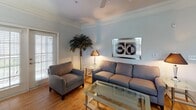 Located at 5806 Ogeechee Rd, Unit 317, in Savannah, Georgia, this single-floor residence offers a thoughtfully designed layout with a seamless flow between living spaces. The entryway opens to a dining area finished with light hardwood-style flooring and elegant crown molding, providing a welcoming first impression. Adjacent to the dining space, the kitchen is outfitted with rich dark cherry cabinetry, dark granite-style countertops, black appliances including a range, microwave, refrigerator, and dishwasher, plus a double-basin stainless steel sink framed by a window with views of lush greenery outside. The living room is a bright, comfortable space featuring crown molding, hardwood-style flooring, a ceiling fan, and French doors that invite natural light and provide outdoor access. Two bedrooms offer carpeted flooring, ceiling fans, and windows that allow for natural light, creating restful and functional retreats. The bathroom includes tile flooring, a single vanity, and a tub-shower combination. Throughout the residence, a neutral color palette and consistent finishes create a cohesive and inviting atmosphere well-suited to comfortable everyday living in Savannah.