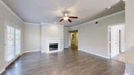 This single-story, 3-bedroom, 2-bathroom home offers a well-designed layout that balances comfort and functionality. The open living room is a standout space, featuring elegant crown molding, a ceiling fan, rich hardwood-style flooring, and a classic white-mantled fireplace as a central focal point. Natural light pours in through multiple windows and a set of French doors, creating a bright and welcoming ambiance throughout.

The kitchen is equipped with contemporary flat-front wood-toned cabinetry, granite countertops, and stainless steel appliances including a range, microwave, and dishwasher — providing both style and practicality for everyday use.

The three bedrooms offer a mix of hardwood-style and plush carpet flooring. The generously sized primary bedroom provides a comfortable retreat, while the additional bedrooms feature large windows with views of surrounding greenery and ceiling fixtures for added comfort. Crown molding carries through several rooms, lending a cohesive, polished feel.

Both bathrooms are clean and functional, with one featuring a full tub-shower combination accented by white tile and warm wood-toned cabinetry. A dedicated laundry room houses a full-size washer and dryer with built-in shelving for extra storage. Two closets and a hallway round out this efficiently planned home.
