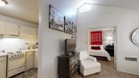 This efficiently designed 2-bedroom, 1-bathroom residence offers a thoughtfully organized single-floor layout that maximizes every square foot. The open-concept kitchen features white cabinetry, a full-size refrigerator, and a range, complemented by wood-look flooring that adds warmth to the space. A dedicated dining area sits adjacent to the kitchen, providing a convenient setup for everyday meals. The living area benefits from a large picture window that invites generous natural light and views of surrounding greenery, creating a bright and airy atmosphere. The primary bedroom is a comfortable retreat, featuring plush carpet, a wall-mounted air conditioning unit, and shuttered windows that allow for adjustable light control. A walk-in closet off the primary bedroom provides well-organized shelving and hanging space for ample storage. The second bedroom offers additional flexibility for use as a guest room or home office. The bathroom includes a full soaking tub and shower combination with clean tile surround. Throughout the residence, textured ceilings and neutral wall tones provide a versatile backdrop. The overall layout is practical and cohesive, making efficient use of the available space while maintaining a comfortable, livable feel.