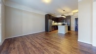 Located at 525 Kempsville Rd in Virginia Beach, Virginia, this single-floor residence offers a thoughtfully designed layout with modern finishes throughout. The open-concept living and kitchen area is anchored by rich hardwood-style flooring that flows seamlessly from room to room, creating a cohesive and inviting atmosphere. A set of glass-paned French doors with a transom window floods the living space with natural light while providing a pleasant outdoor view.

The kitchen is a standout feature, showcasing dark espresso cabinetry paired with granite countertops, a tile backsplash, and a full suite of stainless steel appliances, including a refrigerator, electric range, over-the-range microwave, and dishwasher. Under-cabinet lighting adds a polished touch, while a peninsula with seating provides additional prep and dining space.

The bedroom offers plush carpeting and a distinctive bay window arrangement that brings in abundant natural light and outdoor scenery, creating a calm and restful retreat. The bathroom is finished with a dark-cabinetry vanity, white countertop, and a large mirror, maintaining the consistent modern aesthetic found throughout the unit. The electrical panel is conveniently accessible near the kitchen entry. Overall, the space presents a clean, contemporary design with practical functionality.