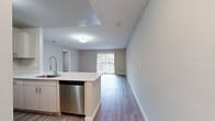 Located at 4793 N Pine Hills Rd in Pine Hills, Florida, this single-story home offers a practical and modern layout with three bedrooms and two full bathrooms. The open-concept living and kitchen area forms the heart of the home, bathed in natural light from a large sliding glass door that leads to the outdoors. The living room features wood-look flooring and a textured ceiling, creating a warm, welcoming atmosphere with ample space for everyday living. The kitchen is well-appointed with stainless steel appliances — including a gas range, refrigerator, built-in microwave, and dishwasher — complemented by light wood cabinetry, white quartz-style countertops, and a deep single-basin sink with a modern pull-down faucet. The galley-style layout maximizes efficiency while connecting seamlessly to the living area. The three bedrooms are bright and neutral-toned, each finished with light wood-look flooring and clean white trim. The primary bedroom offers a comfortable and functional footprint. Both bathrooms are finished consistently with wood-look flooring, light vanities with white countertops, and full tub-shower combinations with tiled surrounds. Natural light enters through slatted blinds in each bathroom. The home's clean, neutral palette and modern finishes make it a move-in ready residence in the Pine Hills community.