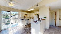 Located at 1904 College Blvd in Oceanside, California, this single-floor residence offers a well-organized layout designed for comfortable everyday living. The living room serves as the heart of the home, highlighted by striking vaulted ceilings that lend an open, airy feel to the space. Large windows allow generous natural light to pour in, illuminating the plush carpeting and creating a bright, welcoming atmosphere.

The kitchen is efficiently designed with white cabinetry, light countertops, and wood-look flooring that extends throughout the main areas. A peninsula provides additional counter space and a natural divider between the kitchen and living areas. A sliding glass door off the kitchen opens to a private balcony, offering a seamless indoor-outdoor connection with views of the surrounding neighborhood.

The bedrooms are carpeted and each features dual sliding-door closets, providing ample storage and a clean, streamlined look. The warm, neutral tones of the walls complement the overall palette of the home, creating a cohesive and calming environment throughout.

The bathrooms are finished with wood-look flooring, neutral walls, and functional vanity cabinetry. One bathroom features a shower-tub combination, adding practicality to the layout. Throughout the residence, the design maintains a consistent, understated aesthetic that balances comfort and functionality.