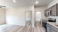 Located at 3055 Flynn Rd in Dothan, Alabama, this one-bedroom, one-bathroom unit offers a well-designed layout with modern finishes throughout. Light gray luxury vinyl plank flooring flows seamlessly across the entire space, complementing the clean white walls and recessed lighting that create a bright, contemporary atmosphere.

The kitchen is a standout feature, equipped with dark gray shaker-style cabinetry, granite countertops, a stainless steel undermount sink, and a full suite of stainless steel appliances including a range, over-the-range microwave, and refrigerator. The kitchen opens conveniently toward the main living area and entry door.

The spacious primary bedroom is generously proportioned and filled with natural light from a large window overlooking a scenic outdoor landscape. A ceiling fan with integrated lighting adds comfort and function, while a wall-mounted mini-split unit provides individualized climate control. A dedicated closet provides practical storage.

The bathroom is well-appointed with a dark-stained vanity topped with granite, a brushed nickel faucet and towel bar, and a full tub-shower combo with clean white surround. The matching vinyl plank flooring ties the space together cohesively.

Overall, the unit presents a clean, move-in-ready aesthetic with thoughtful details and a functional floor plan suited for comfortable everyday living.