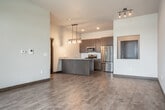 Located at 641 W Main St in Sun Prairie, WI, this thoughtfully designed one-bedroom, one-bathroom unit offers a comfortable and modern living experience across a single floor. The open-concept layout seamlessly connects the kitchen and living room, creating an airy, functional space ideal for everyday living and entertaining. The kitchen is a standout feature, boasting a large granite-topped island with a double stainless steel sink, sleek dark-toned cabinetry extending to the ceiling, a subway tile backsplash, and a full suite of stainless steel appliances including a gas range, microwave, and refrigerator. Contemporary pendant lighting adds a stylish finishing touch overhead. The living area features wood-look tile flooring and a sliding glass door with vertical blinds that opens to a private patio, inviting natural light throughout. The carpeted bedroom is a well-proportioned retreat with a ceiling fan, a window with outdoor views, and a dedicated closet with built-in shelving. An additional closet provides extra storage. The bathroom is elegantly appointed with a granite-topped vanity, dark cabinetry, an LED-framed mirror, and a tub/shower combination. In-unit laundry completes this well-equipped home.