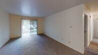Located at 1510 Locust St in Elkhart, Indiana, this single-floor unit offers a well-organized and functional layout across multiple living spaces. The entryway welcomes residents with neutral-toned walls, carpet flooring, and decorative wainscoting paneling, creating a tidy and clean first impression.

The living area is generously sized and features plush carpeting, a sliding glass door that fills the room with natural light and provides views of the surrounding greenery. The kitchen is equipped with warm-toned wooden cabinetry, laminate countertops, a stainless steel sink, a dishwasher, electric range, and a full-size refrigerator, all under a recessed ceiling detail that adds architectural interest.

The bedrooms are carpeted and bright, each featuring vertical-blind windows that allow for adjustable natural light. The neutral color palette throughout creates a calm and cohesive atmosphere.

Two bathrooms serve the unit. One features a full tub-shower combination with classic white tile surround and wood-accented vanity. The second includes a wide countertop with an undermount sink, a large mirror, and stylish overhead vanity lighting. Both bathrooms include wood-look flooring and safety grab bars, offering practical convenience throughout.