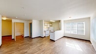 Located at 110 Southeast Washington Street in Hillsboro, Oregon, this single-floor, 2-bedroom, 2-bathroom unit offers a well-organized layout across a comfortable footprint. The open-concept living and dining area is bright and airy, featuring wood-style laminate flooring and large windows that invite generous natural light and views of surrounding greenery. A dedicated entrance leads seamlessly into the main living space.

The galley-style kitchen is efficiently designed with white cabinetry trimmed in warm wood tones, ample counter space, a double-basin sink, and white appliances including a range and refrigerator. A peninsula breakfast bar connects the kitchen to the combined living and dining area.

Both bedrooms are carpeted for comfort and include sliding-door closets with built-in shelving. The primary bedroom features its own en-suite bathroom with a vanity, large mirror with accent lighting, and convenient access. A second full bathroom includes a tub/shower combination, single-basin vanity with storage, and wood-style flooring.

The unit also includes a dedicated laundry area and three closets for additional storage. A utility closet houses the water heater. Clean white walls and neutral finishes throughout create a cohesive, move-in-ready aesthetic.