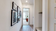 This single-floor residence presents a thoughtfully designed layout connecting living, sleeping, and functional spaces with a consistent modern aesthetic. Light wood-look flooring and crisp white walls flow throughout, creating a bright, cohesive environment.

The kitchen is well-equipped, featuring white shaker cabinetry extending to the ceiling, granite countertops, a marble-style tile backsplash, and a full suite of stainless steel appliances including a range, microwave, dishwasher, and refrigerator. Ample counter space and storage make the kitchen both practical and visually refined.

The living area benefits from generous natural light through floor-to-ceiling sheer-draped windows, providing an airy, open atmosphere. A welcoming hallway connects the rooms, lined with gallery-style wall art and built-in shelving.

The bedrooms are generously proportioned, each featuring large windows with sheer drapery that fills the rooms with soft natural light. The primary bedroom includes access to a walk-in closet with built-in shelving systems and an en-suite bathroom finished with granite-topped white vanities and wood-look tile flooring. A second bathroom mirrors this refined finish. The overall ambiance is clean, modern, and welcoming throughout.