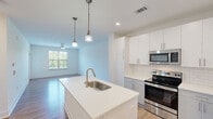 Located at 820 Clawson Pl in Fort Mill, SC, this well-appointed one-bedroom, one-bathroom unit offers a thoughtfully designed single-floor layout. The open-concept living room and kitchen area serves as the heart of the home, bathed in natural light from large windows with views of surrounding greenery. Light-toned hardwood-style flooring runs throughout the main living areas, complementing the clean, neutral color palette.

The kitchen is a standout feature, equipped with stainless steel appliances including a range, microwave, and refrigerator. White upper cabinetry is paired with light gray lower cabinets, accented by a classic subway tile backsplash. A large island with a quartz countertop and undermount sink provides additional workspace and storage, with pendant lighting adding a modern touch overhead.

The bedroom offers a comfortable, carpeted retreat with a ceiling fan and a window overlooking the outdoors. Two closets provide ample storage throughout the unit. The bathroom features a tub-shower combination with tile surround, a quartz-topped vanity, and wood-style flooring, with direct access to an additional closet. The living area includes a private entry door with a transom window, enhancing both light and accessibility.