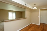 This single-floor residence offers a practical and comfortable layout across several distinct living areas. The kitchen is well-appointed with white raised-panel cabinetry extending to the ceiling, a granite-toned countertop, a double stainless steel sink, and white appliances including a gas range and refrigerator. Warm hardwood flooring runs throughout the kitchen, which connects to the living area via a pass-through window, enhancing the open feel of the space.

The spacious living room features plush carpeting and a sliding glass door that opens to a balcony, allowing for generous natural light and outdoor views. Additional carpeted rooms, each equipped with ceiling fans and multiple windows, provide comfortable and well-lit spaces with views of surrounding greenery.

The bathrooms are finished with light tile flooring, white subway tile backsplashes, white vanity cabinetry, and granite-toned countertops. One bathroom includes a tub-shower combination with a striped tile surround, while another features a separate vanity area with a dedicated towel bar and storage closet. The overall aesthetic throughout the home is neutral and cohesive, with warm beige tones creating a calm, inviting ambiance.