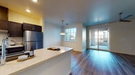Located at 925 W Lathrop Rd in Manteca, California, this contemporary single-floor residence offers a thoughtfully designed open-concept layout with consistent wood-look flooring throughout. The kitchen is a standout feature, showcasing rich dark cabinetry, light quartz countertops, stainless steel appliances including a refrigerator and electric range, and a dishwasher. A peninsula counter provides additional prep space and creates a natural transition into the living area, which is bathed in natural light from a large window and sliding glass doors that open to a private balcony. The galley-style kitchen corridor leads to an in-unit laundry area with a washer, adding everyday convenience. The primary bedroom offers generous proportions, a large window framing neighborhood views, and direct access to a well-appointed en-suite bathroom featuring dual under-mount sinks, quartz countertops, dark cabinetry, and wood-look tile flooring. A secondary bedroom provides a clean, bright space with ample room and dedicated closet storage. The second full bathroom includes a shower-tub combination and matching finishes. A spacious walk-in closet with built-in shelving and hanging rods adds practical storage. Clean neutral walls and recessed lighting complete the polished, modern aesthetic throughout.