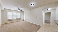 Located at 546 Frontier Rd in Lawrence, Kansas, this single-floor unit offers a thoughtfully designed layout with a comfortable and functional living environment. The open-concept living area is finished with plush carpeting, clean neutral walls, and ceiling fans throughout, creating a bright and welcoming atmosphere. Large windows allow natural light to flow freely into the space, enhancing its airy feel.

The kitchen is well-appointed with white cabinetry featuring beadboard detailing, rich dark granite countertops, a breakfast bar peninsula, and a full suite of appliances including an electric range, microwave, refrigerator, and dishwasher. Tile flooring runs throughout the kitchen and entryway areas. A convenient in-unit laundry area is accessible directly from the kitchen.

The bedrooms are carpeted and each feature ceiling fans and windows with blinds. The primary bedroom offers direct access to a full bathroom equipped with a tub/shower combination with sliding glass doors, granite countertop vanity, and tile flooring. An additional half bathroom with a pedestal sink and tile flooring provides added convenience for guests.

The overall design is clean and neutral, offering a move-in-ready space with practical finishes throughout.