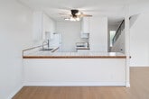 Located at 440 Canyon Drive in Oceanside, CA, this two-story, 2-bedroom, 2-bathroom home offers a well-organized layout spread across two floors. The ground floor welcomes you through a dedicated entrance that opens to a combined dining and living area filled with natural light, enhanced by light wood-style flooring. The kitchen features white cabinetry, tile countertops with wood-trim edging, a ceiling fan, and ample counter space, flowing seamlessly toward the staircase. A private patio off the lower level provides an outdoor retreat framed by lush greenery and mature trees. Upstairs, the second floor hosts both bedrooms, each bathed in natural light from large windows and sliding glass doors. The primary bedroom offers direct access to a balcony overlooking the surrounding landscape, while the second bedroom features a wide window with views of palm trees. Four closets are distributed throughout the home for generous storage. The two bathrooms are clean and functional, with one featuring a wide vanity, large mirror, and tile flooring, and the other with wood-style flooring and a separate toilet area. A carpeted staircase with a sleek black metal railing connects both levels, adding a refined design touch to this bright and practical Southern California home.