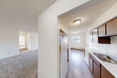 Located at 5216 Perry Rd in Grand Blanc, MI, this single-floor, 2-bedroom, 1-bathroom residence offers a functional and well-organized layout. The galley-style kitchen features warm wood cabinetry, white appliances including an electric range and refrigerator, a double sink, and durable wood-look flooring. It opens directly into the dining area, creating a convenient combined space filled with natural light from a window overlooking the exterior. The living area is carpeted and connects seamlessly to the rest of the home through a central hallway. Both bedrooms are carpeted and bright, benefiting from natural light through windows with vertical blinds. The spacious primary bedroom includes direct sightlines to the bathroom and features baseboard heating. The second bedroom is equipped with a wall air conditioning unit, baseboard heat, and two windows. Throughout the unit, five closets provide generous storage. The full bathroom is well-appointed with a single-sink vanity with wood cabinetry, a large mirror with overhead lighting, and a tub/shower combo with tile surround, all finished with wood-look flooring. Textured ceilings are consistent throughout the home.