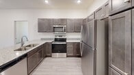 Located at 4209 Brett Ave in Sioux Falls, South Dakota, this single-floor unit offers a thoughtfully designed layout with modern finishes throughout. The kitchen serves as a standout feature, showcasing rich dark-stained shaker-style cabinetry paired with granite-look countertops and a full suite of stainless steel appliances, including a range, over-the-range microwave, and refrigerator. Light wood-look tile flooring runs through the kitchen and living areas, lending a clean, contemporary feel.

The living area is bright and open, featuring recessed lighting and a sliding glass door that opens onto a private balcony with a metal railing, offering views of the surrounding neighborhood. The bedrooms are finished with plush carpet, neutral walls, and windows that bring in natural light. Each room is serviced by flush-mount ceiling fixtures and floor vents. A generously sized walk-in closet features wire shelving at multiple heights, maximizing storage efficiency.

The bathroom includes a full-size soaking tub and shower combination with crisp white surrounds and chrome fixtures. Throughout the unit, clean lines, neutral tones, and functional design elements create a cohesive and move-in-ready living environment.