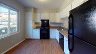 Located at 5581 Burnlee Pl in Raleigh, NC, this two-story home offers a well-organized layout across two levels connected by a staircase. The kitchen is equipped with white cabinetry, granite-style countertops, and black appliances including a range, dishwasher, and refrigerator, all set atop durable hardwood-style flooring. A window brings in natural light, making the kitchen feel bright and practical.

The living area is generously sized, featuring plush carpeting, a ceiling fan with light fixture, and a sliding glass door flanked by vertical blinds that opens to the outdoors. A pass-through window connects the living space to the kitchen, adding an open and communicative feel between the areas.

The bedrooms are carpeted and well-proportioned, each outfitted with ceiling fans and large windows dressed in vertical blinds that allow for ample natural light. Several bedrooms include walk-in or louvered-door closets, providing excellent storage. The neutral gray wall tones throughout create a clean, cohesive aesthetic.

The bathroom features a tiled tub-shower combination, mosaic tile flooring, a granite-top vanity with an undermount sink, and a bright window. The overall design of the home is practical and comfortable, suited for everyday living in a residential Raleigh neighborhood.