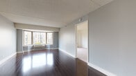 Located at 7912 River Rd in North Bergen, NJ, this single-floor residential unit offers a well-designed layout with a variety of functional spaces. The main living area makes a strong impression with its rich, dark hardwood flooring that reflects natural light streaming in through large corner windows. The open sightlines and neutral gray walls create a clean, versatile atmosphere, with a closet and direct access to the kitchen nearby.

The galley-style kitchen is thoughtfully appointed with white shaker cabinetry, granite countertops, a tile backsplash, and a full suite of stainless steel appliances including a refrigerator, range, dishwasher, and over-the-range microwave. Dark hardwood flooring continues throughout this space, adding warmth and continuity.

The bedrooms are carpeted for comfort and feature individual wall-mounted HVAC units and windows overlooking the surrounding neighborhood, bringing in natural light and outdoor views. The bathrooms are finished with light tile flooring, a dark-cabinet vanity with a granite countertop, a framed mirror, and a tiled shower-over-tub combination, offering a clean and functional design. The overall ambiance of the unit is bright, neutral, and move-in ready.