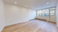 Located at 1 Marquette in Toronto's Lawrence Heights neighbourhood, this thoughtfully renovated one-bedroom, one-bathroom unit offers a clean, modern aesthetic throughout. Light-toned hardwood flooring runs continuously across the entire space, creating a cohesive and airy feel complemented by crisp white walls and recessed pot lighting.

The open-concept living and dining area is generously proportioned, bathed in natural light through wide windows that frame views of mature trees and the surrounding neighbourhood. Baseboard heating units run along the window walls, providing efficient warmth. Access to two balconies extends the living space outward, offering pleasant outdoor views of tree-lined streets.

The kitchen is functional and well-positioned, with a window allowing natural light and neighbourhood views. The bedroom is a comfortable size, featuring mirrored sliding closet doors and a window with a radiator beneath it, adding both storage and natural brightness to the room.

The bathroom is a standout feature, finished with elegant marble-effect wall and floor tiles, a soaker tub with a handheld shower, warm wood vanity cabinetry, and brushed gold fixtures that lend a refined, contemporary touch. A dedicated closet adds practical storage to round out this well-appointed unit.