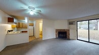 Located at 2389 South Southeast Boulevard in Spokane, WA, this single-floor unit offers a practical and comfortable layout across several well-defined living spaces. The open living room serves as the heart of the unit, anchored by a stone-surround wood-burning fireplace that adds warmth and character. Plush carpeting, a ceiling fan with light fixture, a textured ceiling, and a wall-mounted AC unit complete the space. A sliding glass door floods the room with natural light and provides outdoor access. The kitchen is outfitted with warm wood cabinetry, light countertops with a tile backsplash, a double sink, and white appliances including a range, refrigerator, and dishwasher, all set over easy-care wood-look flooring. The bedrooms are carpeted and bright, each featuring large windows with views of surrounding greenery, baseboard heating, and a textured ceiling. One bedroom includes a built-in closet and sliding door access to the outdoors. The bathroom is thoughtfully divided, with a vanity area featuring a wide mirror and wood cabinetry separated from the toilet and tub/shower compartment, which is fully tiled and finished with wood-look flooring throughout.