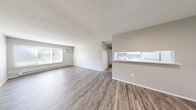 Located at 1105 S Wheeling St in Oregon, OH, this 2-bedroom, 1-bathroom unit offers a practical and well-designed single-floor layout. The open-concept main living area seamlessly combines the living room, dining room, and kitchen into one connected space. Light gray LVP flooring runs throughout the common areas, complemented by neutral gray walls and white trim, creating a clean and cohesive aesthetic. A large window in the living room allows natural light to fill the space, while a wall-mounted A/C unit and baseboard heaters provide year-round climate control. The kitchen features white cabinetry and appliances, accessible via a pass-through countertop that opens to the living and dining areas. Both bedrooms are carpeted in neutral gray tones and include natural light from windows, baseboard heating, and generous closet space — with the primary bedroom offering a walk-in closet. The unit includes an impressive five closets in total, providing abundant storage throughout. The bathroom is finished with a full tub-shower combination featuring white tile surround. The textured ceilings and consistent neutral palette give the entire unit a move-in-ready, well-maintained character.
