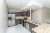 Located at 18248 W 12 Mile Rd in Southfield, Michigan, this single-floor residence offers a cohesive and functional layout designed for comfortable everyday living. The kitchen is a standout feature, showcasing rich dark espresso cabinetry, granite countertops, light tile flooring, and a full suite of stainless steel appliances including a refrigerator, range, and over-the-range microwave. The open living and dining area is finished with light-toned luxury vinyl flooring and neutral warm beige walls, creating a bright and welcoming atmosphere. A built-in closet with rod storage is conveniently located within the living space. The bedrooms are carpeted and generously sized, each featuring tray ceilings, large windows that bring in natural light and outdoor views, and dedicated closets with built-in shelving and hanging rods. Two bathrooms serve the residence: one features a tiled tub-shower combination, granite-topped dark vanity, and tile flooring, while the second offers a frameless glass-enclosed walk-in shower with coordinating tile surround and a matching granite vanity. Throughout the space, warm neutral tones and consistent finishes create a polished and cohesive aesthetic.