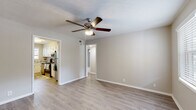 This single-floor residence offers a clean, functional layout with a cohesive neutral color palette throughout. The living area features light hardwood-style flooring, crisp white trim, and a ceiling fan with integrated lighting, creating an airy and comfortable environment. Multiple rooms with hardwood-style flooring provide versatile living and flex spaces, each equipped with ceiling fans and windows dressed with blinds that allow natural light to filter in.

The bedrooms are finished with plush carpeting for added comfort and also feature ceiling fans, generous wall space, and windows with outdoor views. The layout, as seen in the dollhouse overview, is compact yet efficiently organized, with clearly defined rooms connected by a central hallway.

The kitchen is a standout feature, boasting white cabinetry, granite-style countertops, stainless steel appliances including a dishwasher and electric range, and a window above the sink that brings in natural light. The hardwood-style kitchen flooring ties seamlessly into the adjoining living areas.

The bathroom is finished in soft neutrals with a white vanity, integrated sink, framed mirror, and modern multi-bulb light fixture, lending a clean and polished look. Overall, the space presents a practical and well-maintained interior with consistent finishes throughout.