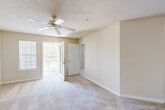 This single-floor, 2-bedroom, 2-bathroom home offers a practical and comfortable layout designed for everyday living. The entrance opens into a hallway that transitions seamlessly into the combined dining and living area, which features neutral-toned carpet, a textured ceiling, and access to an outdoor area via a glass-paned French door that brings in generous natural light. The kitchen is well-equipped with warm wood cabinetry, white appliances including a gas range and dishwasher, a double-basin sink, and a peninsula breakfast bar that connects the kitchen to the living space. Tile flooring runs throughout the kitchen and wet areas, complementing the carpet found in the main living and bedroom spaces. A dedicated laundry area and utility room provide added convenience. The primary bedroom is generously sized, featuring a ceiling fan, a window with outdoor views, and access to a private bathroom. Four closets throughout the home — including a walk-in closet outfitted with wire shelving — provide extensive storage. The secondary bedroom is bright and carpeted with a window overlooking the exterior. Both bathrooms include a vanity with a mirror, tile flooring, and a shower-tub combination. The overall ambiance is clean, neutral, and move-in ready.