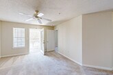 This single-floor, 2-bedroom, 2-bathroom home offers a practical and comfortable layout designed for everyday living. The entrance opens into a hallway that transitions seamlessly into the combined dining and living area, which features neutral-toned carpet, a textured ceiling, and access to an outdoor area via a glass-paned French door that brings in generous natural light. The kitchen is well-equipped with warm wood cabinetry, white appliances including a gas range and dishwasher, a double-basin sink, and a peninsula breakfast bar that connects the kitchen to the living space. Tile flooring runs throughout the kitchen and wet areas, complementing the carpet found in the main living and bedroom spaces. A dedicated laundry area and utility room provide added convenience. The primary bedroom is generously sized, featuring a ceiling fan, a window with outdoor views, and access to a private bathroom. Four closets throughout the home — including a walk-in closet outfitted with wire shelving — provide extensive storage. The secondary bedroom is bright and carpeted with a window overlooking the exterior. Both bathrooms include a vanity with a mirror, tile flooring, and a shower-tub combination. The overall ambiance is clean, neutral, and move-in ready.