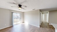 This single-story residence on Curtis Ln SE in Cleveland, Tennessee offers a thoughtfully designed layout across a compact yet efficient floor plan. The combined kitchen and living area serves as the heart of the home, where wood-style plank flooring, neutral wall tones, and a ceiling fan create a bright, inviting atmosphere. Sliding glass doors lead to an outdoor balcony, allowing natural light to fill the living space and providing a direct connection to the exterior.

The kitchen is equipped with stainless steel appliances, including a range, microwave, and refrigerator, complemented by white shaker-style cabinetry and granite countertops. A built-in overhead light panel adds practical illumination to the workspace.

The two bedrooms feature ceiling fans and natural light from windows with blinds. The primary bedroom is carpeted, providing a softer underfoot feel, while the second bedroom showcases wood-style flooring. All three bathrooms are finished consistently, each featuring granite-topped vanities and tub-shower combinations with large-format marble-style tile surrounds and brushed nickel fixtures. The textured ceilings and clean white trim complete the cohesive, move-in-ready aesthetic throughout.