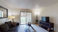Located at 3108 S Jefferson Ave in Springfield, Missouri, this single-floor residence offers a practical and comfortable layout with distinct living, dining, sleeping, and kitchen areas. The living room is a welcoming space with soft carpet flooring, a textured ceiling, and a large sliding glass door fitted with vertical blinds that allow generous natural light and provide a view of the surrounding greenery outdoors. A dedicated dining area sits adjacent to the living room, featuring louvered closet doors that add a classic touch, alongside ample space for a dining set. The galley-style kitchen is efficiently designed with dark wood cabinetry lining both walls, white countertops, a gas range, full-size refrigerator, and a double-basin sink — providing everything needed for everyday cooking. The bedroom is a restful retreat, highlighted by a large window that frames outdoor views of mature trees and landscaped grounds, complemented by plush carpet and a textured ceiling. The full bathroom features a shower-tub combination with a decorative curtain, a vanity with countertop space, and tile flooring. Throughout the unit, neutral tones and consistent flooring create a cohesive and inviting atmosphere.