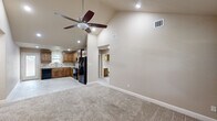 This single-story, 2-bedroom, 3-bathroom home is designed for comfortable everyday living, featuring a thoughtful open-concept layout that connects the main living areas seamlessly. The living room makes an immediate impression with its vaulted ceiling, ceiling fan with integrated lighting, and plush carpet flooring, creating a warm and inviting atmosphere. A tiled entryway greets visitors at the front door, framed by tall ceilings that enhance the sense of space.

The kitchen is outfitted with rich wood cabinetry, granite-style countertops, tile flooring, and black appliances, including a full-size refrigerator. A pendant light above the sink area adds a decorative touch, while ample counter space supports practical meal preparation.

The primary bedroom features a distinctive tray ceiling accented with crown molding, a ceiling fan, soft carpet flooring, and a window overlooking the outdoors. It is complemented by a dedicated closet with built-in shelving and a window for natural light. The primary bathroom includes a walk-in tiled shower with decorative mosaic accents and a wood-vanity with light countertops.

The secondary bedroom offers crown molding and plush carpet, served by a full bathroom with a tub-shower combination and dark wood cabinetry. A utility room, additional hallways, and a third bathroom complete the efficient floor plan of this well-finished home.