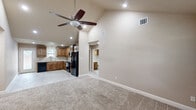 This single-story, 2-bedroom, 3-bathroom home is designed for comfortable everyday living, featuring a thoughtful open-concept layout that connects the main living areas seamlessly. The living room makes an immediate impression with its vaulted ceiling, ceiling fan with integrated lighting, and plush carpet flooring, creating a warm and inviting atmosphere. A tiled entryway greets visitors at the front door, framed by tall ceilings that enhance the sense of space.

The kitchen is outfitted with rich wood cabinetry, granite-style countertops, tile flooring, and black appliances, including a full-size refrigerator. A pendant light above the sink area adds a decorative touch, while ample counter space supports practical meal preparation.

The primary bedroom features a distinctive tray ceiling accented with crown molding, a ceiling fan, soft carpet flooring, and a window overlooking the outdoors. It is complemented by a dedicated closet with built-in shelving and a window for natural light. The primary bathroom includes a walk-in tiled shower with decorative mosaic accents and a wood-vanity with light countertops.

The secondary bedroom offers crown molding and plush carpet, served by a full bathroom with a tub-shower combination and dark wood cabinetry. A utility room, additional hallways, and a third bathroom complete the efficient floor plan of this well-finished home.