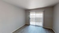 Located at 9350 N 67th Ave in Peoria, Arizona, this single-story unit presents a clean, updated interior with a neutral color palette and modern finishes throughout. The open living area is bright and welcoming, featuring wood-style laminate flooring and a sliding glass door fitted with vertical blinds that leads to a private outdoor patio, allowing natural light to fill the space while providing direct outdoor access.

The galley-style kitchen is efficiently designed with white cabinetry offering generous storage, light quartz-style countertops, a stainless steel sink, and a full suite of appliances including a stainless electric range, refrigerator, and dishwasher. A pass-through opening connects the kitchen to the adjacent dining area, which features matching wood-style flooring and a flush-mount light fixture overhead.

The bedroom is carpeted and offers a quiet, comfortable retreat with a closet and ample wall space. The bathroom is well-appointed with a tub-shower combination, a white-framed vanity mirror, a single-basin sink with stone-look countertop, and coordinating wood-style flooring. Throughout the unit, the light gray walls and clean white trim create a cohesive, move-in-ready atmosphere.