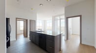 Located at 6518 Milwaukee St in Madison, Wisconsin, this thoughtfully designed single-floor unit offers a clean, contemporary aesthetic throughout. The open-concept layout centers around a well-appointed kitchen featuring a large island with granite countertops, an integrated sink, and dark cabinetry. A full suite of stainless steel appliances — including a side-by-side refrigerator, electric range, and microwave — is complemented by extensive gray upper cabinetry providing generous storage. Light wood-plank flooring flows through the main living areas, creating a warm contrast against the crisp white walls and dark finishes.

Oversized windows and glass balcony doors flood the space with natural light and frame expansive views of the surrounding landscape. The bedrooms are bright and airy, each benefiting from large windows that continue to highlight the scenic outdoor vistas. Two bathrooms are finished with neutral tile flooring, gray shaker-style vanities, white quartz countertops, and frameless mirrors. One bathroom includes a walk-in glass shower, while the other features a full tub-shower combination with floor-to-ceiling tile surround. An in-unit laundry closet houses a full-size front-loading washer and dryer, adding everyday convenience to this polished and functional living space.