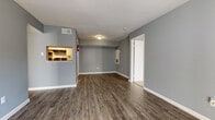 This single-floor residence offers a well-organized layout designed for functional, everyday living. The open living area is finished with durable dark hardwood-style flooring and painted in a cool, neutral gray palette throughout, creating a cohesive and modern aesthetic. White baseboards provide a clean contrast against the gray walls, lending the space a crisp, finished look.

The kitchen is efficiently laid out with white cabinetry, granite-style countertops, a subway tile backsplash, and black appliances including an electric range, dishwasher, and refrigerator. A pass-through window connects the kitchen directly to the living area, enhancing the open feel of the space.

The bedrooms are carpeted for comfort and each features a ceiling fan with light, natural light from windows with horizontal blinds, and ample wall space. The rooms offer a quiet, comfortable retreat.

The bathrooms are clean and functional, featuring granite-style countertops, white vanity cabinetry, a framed mirror, and a full tub-shower combination with white tile surround and brushed nickel fixtures. Textured gray walls add a subtle design detail to the bathrooms.

Overall, the space presents a tidy, move-in-ready environment with consistent finishes and a neutral color scheme throughout.