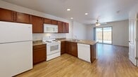 Located at 9924 Railroad Dr in El Paso, TX, this two-story, 2-bedroom, 2-bathroom home offers a well-organized layout spread across two floors. The main level welcomes you through a private covered entryway and opens into a bright, open-concept living and kitchen area. The kitchen is well-appointed with rich cherry wood cabinetry, granite-style countertops, a peninsula with a built-in sink, and white appliances including a range, microwave, dishwasher, and refrigerator. Recessed lighting and a ceiling fan add to the functionality of the space, while a sliding glass door provides access to a patio and brings in natural light. Durable hardwood-style flooring runs throughout the main level. Upstairs, the two carpeted bedrooms offer a comfortable retreat, each featuring ceiling fans with light fixtures and windows that allow natural light in. Both bedrooms include closet storage, and the primary bedroom is generously proportioned. The two bathrooms are finished with matching cherry wood vanities and granite-style countertops; one features a tub-shower combination. A hallway and dedicated closet space complete the upper floor. The exterior presents a low-maintenance landscape with a concrete patio area alongside the building's white lap siding façade.