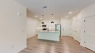 Located at 200 Aycock Avenue in Monroe, GA, this single-story 2-bedroom, 2-bathroom home offers a thoughtfully designed open-concept layout with modern finishes throughout. Light-toned luxury vinyl plank flooring flows seamlessly across the entire space, creating a cohesive and clean aesthetic.

The heart of the home is a well-appointed kitchen and living area combination. The kitchen features crisp white shaker cabinetry with matte black hardware, stainless steel appliances, and a generous island with a granite-style countertop, undermount sink, and seating space. Striking black pendant lights with gold interiors hang above the island, adding a contemporary touch. Recessed lighting and an open sightline to the living room enhance the airy feel.

The living area benefits from multiple windows offering views of surrounding greenery, a ceiling fan, and abundant natural light. Both bedrooms are well-proportioned, each with windows framing outdoor tree views and ceiling fans. The spacious primary bedroom connects to a private bathroom featuring a dual-sink vanity with granite countertops, white cabinetry, and a large mirror. A walk-in closet with wire shelving provides ample storage. A second closet serves additional storage needs. The clean, neutral palette and modern design elements throughout make this a move-in ready home.