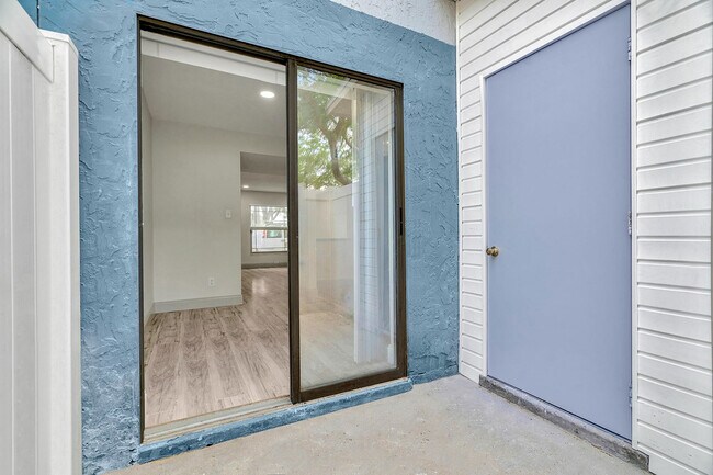 Acogedora entrada al apartamento con moderna puerta corrediza de vidrio que se abre a un interior amplio y luminoso con elegantes pisos de madera. - Temple Crest Townhomes