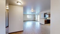 Located in Post Falls, Idaho, this three-bedroom, two-bathroom residence offers a practical and well-organized single-floor layout. The open-concept living room and kitchen area form the heart of the home, featuring light wood-style hard flooring that extends throughout the main living spaces. Large windows and a sliding glass door allow natural light to fill the living area, creating a bright and welcoming atmosphere.

The kitchen is equipped with dark wood cabinetry, a peninsula with overhead range hood, stainless steel refrigerator, black appliances including a dishwasher, and a double sink beneath a window. The layout provides ample counter and storage space for everyday use.

The three bedrooms offer comfortable, carpeted spaces, each with windows that bring in natural light. The spacious primary bedroom provides a generous footprint for furnishing. The two bathrooms feature dark wood vanity cabinetry and light wood-style flooring. One bathroom includes a soaking tub/shower combination, while the other provides a dedicated vanity with generous counter space and a window for ventilation.

A hallway connects the private areas of the home, and a utility room adds practical storage and laundry functionality. The unit also includes access to an exterior door from the kitchen area.