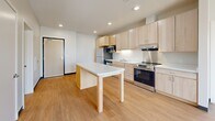 Located at 2260 Bohland Ave in Saint Paul, MN, this 2-bedroom, 1-bathroom unit offers a thoughtfully designed single-floor layout. The open-concept kitchen and living area serves as the heart of the space, featuring light maple cabinetry, a full suite of stainless steel appliances—including a refrigerator, dishwasher, microwave, and range—white countertops, and a central island that doubles as additional prep and dining space. Light wood-tone flooring runs throughout the main living area, lending warmth and continuity. Both bedrooms are carpeted in neutral tones, providing a quiet, comfortable retreat. The primary bedroom is generously proportioned and includes a walk-in closet, while the secondary bedroom offers access to its own closet. Natural light enters through vertical windows, with views of the surrounding neighborhood. The full bathroom is designed with accessibility in mind, featuring light maple cabinetry with a wide vanity, a large mirror, light tile flooring, and grab bars throughout. Three total closets provide ample storage across the unit. Recessed lighting throughout the living areas contributes to a clean, modern aesthetic.