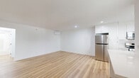 This single-story unit at 3630 Midvale Ave in Los Angeles offers a clean, modern interior defined by a consistent use of light wood vinyl plank flooring and crisp white walls throughout. The open-plan kitchen and living area forms the heart of the unit, creating a versatile shared space. The kitchen is well-appointed with white shaker-style cabinetry, quartz countertops, a stainless steel sink, white subway tile backsplash, and stainless steel appliances including a full-size refrigerator and dishwasher. Natural light enters through windows fitted with white plantation shutters. The living area is a generous open space with a wall-mounted mini-split air conditioning unit for climate control and an in-unit stacked washer and dryer tucked neatly into a dedicated nook. The bedroom is a private, well-sized room featuring its own mini-split unit, windows with exterior views, and a mirrored sliding-door closet that adds a sense of depth and reflects natural light. The overall aesthetic is modern and minimal, with recessed lighting and clean lines that give the unit a bright, move-in ready feel.