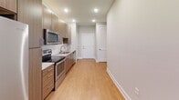 Located at 1106 Scenic Club Dr. in Cary, NC, this single-floor residence offers a clean, contemporary design with thoughtfully selected finishes throughout. The kitchen is a standout feature, outfitted with warm wood-tone cabinetry, granite countertops, a geometric tile backsplash, and a full suite of stainless steel appliances including a refrigerator with ice maker, electric range, built-in microwave, and dishwasher. Light hardwood-style flooring flows seamlessly through the kitchen and into the open living area, which is bathed in natural light from large windows and a glass-paneled door. A ceiling fan with lighting adds both comfort and function to the living space. The bathroom is well-appointed with a granite-topped vanity with wood cabinetry, a soaking tub with white subway tile surround, and hardwood-style flooring. Storage is addressed with a generously sized closet featuring multi-tier wire shelving. Recessed lighting throughout the unit ensures consistent, modern illumination. The neutral color palette of soft grays and warm whites lends the space a bright, move-in-ready ambiance suitable for a variety of interior styles.